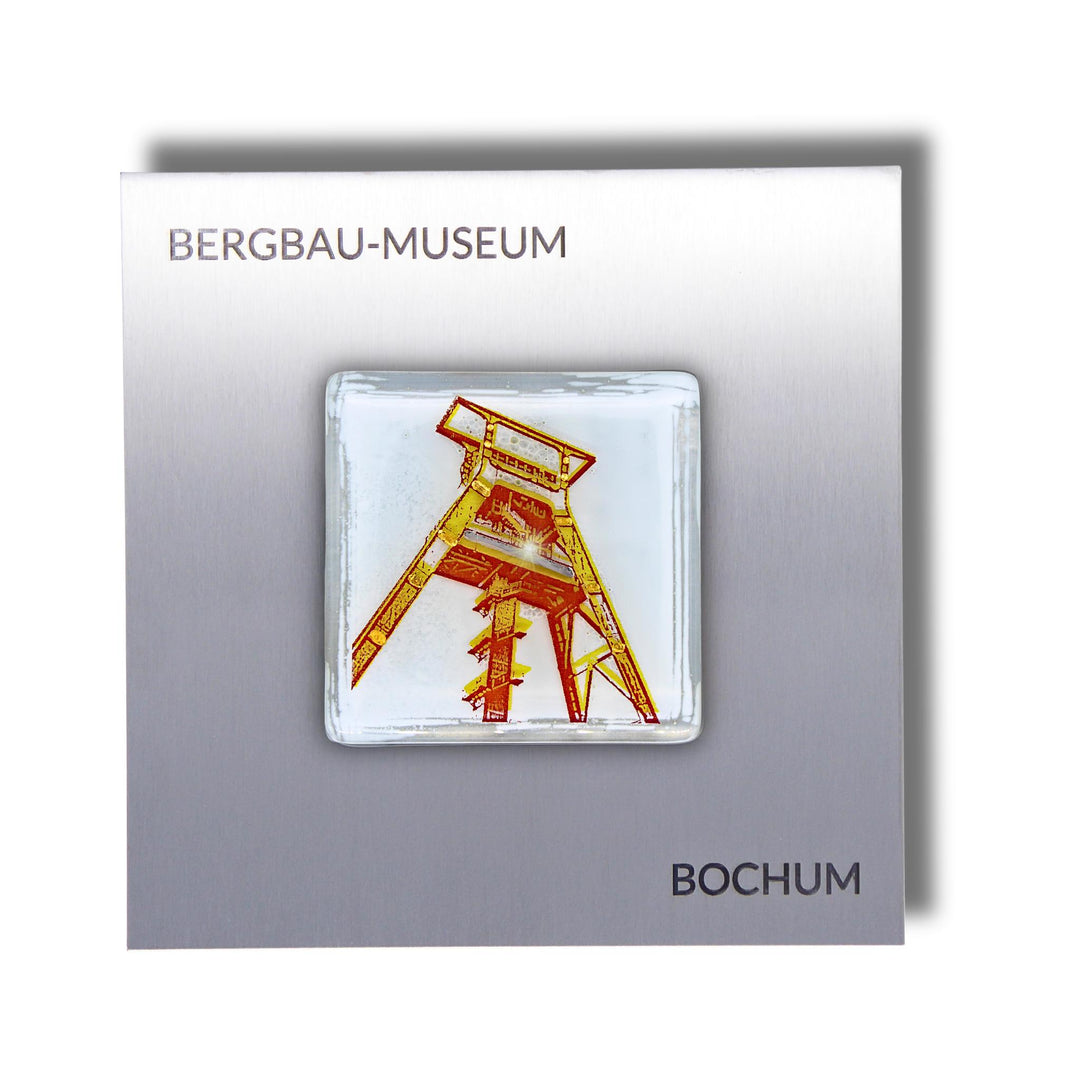Edition 1/12. Pott Glas Wand-Potträt mit Förderturm-Motiv in Gelb. Foto in Schmelzglas auf Edelstahl. Quadratisches Format mit Gravur „Bergbau-Museum Bochum“.