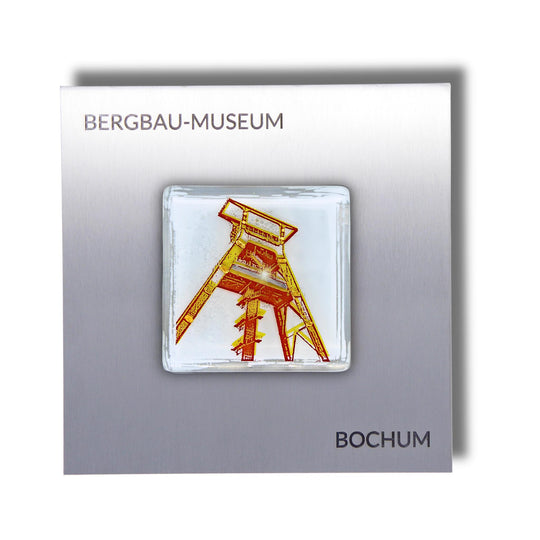 Edition 1/12. Pott Glas Wand-Potträt mit Förderturm-Motiv in Gelb. Foto in Schmelzglas auf Edelstahl. Quadratisches Format mit Gravur „Bergbau-Museum Bochum“.