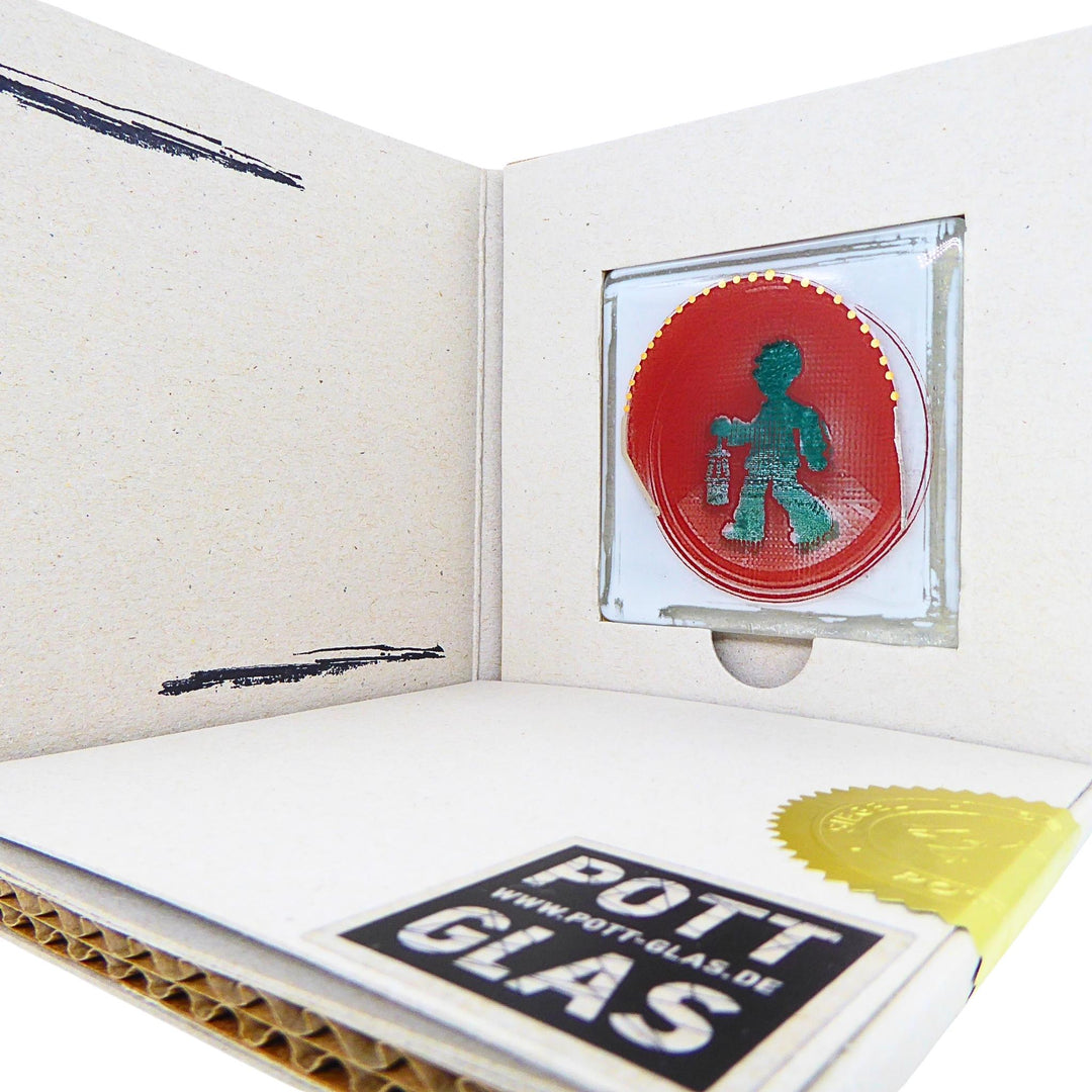 Bochum Edition 01/12. Geöffnete POTT GLAS Blanko-Karte mit grünem Bergmann-Ampel-Motiv als Schmelzglas-Magnet im Karten-Inlay. Darunter die versiegelte Inlay-Karte mit Logo und geprägter Siegelplombe.