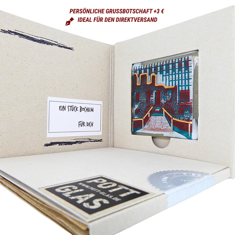 Bochum Edition 11/12. Geöffnete POTT GLAS Karte mit Beschriftungsfeld für eine persönliche Grußbotschaft. Rechts ein Magnet-POTTRÄT aus Schmelzglas mit grünem Haus Weitmar-Motiv sowie Akzenten aus 24-Karat-Flüssiggold und Platin im Karten-Inlay mit Entnahmeaussparung. Hinweis auf die Option „Persönliche Grußbotschaft +3 € für den Direktversand". Darunter die versiegelte Karte mit Logo und geprägter Siegelplombe.