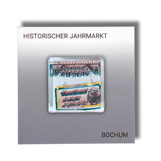 Edition 3/12. Pott Glas Wand-Potträt mit "Raupenbahn"-Motiv in Grün, mit Gold und Platin Akzenten. Foto in Schmelzglas auf Edelstahl. Quadratisches Format mit Gravur „Historischer Jahrmarkt Bochum“.