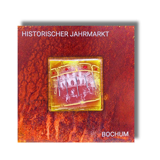 Edition 3/12. Pott Glas Wand-Potträt mit Pferdekarussell-Motiv in Gelb. Foto in Schmelzglas auf Roststahl. Quadratisches Format mit Gravur „Historischer Jahrmarkt Bochum“.