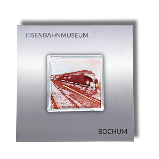 Edition 5/12. Pott Glas Wand-Potträt mit V-Diesellok-Motiv in Rot. Foto in Schmelzglas auf Edelstahl. Quadratisches Format mit Gravur „Eisenbahnmuseum Bochum“.