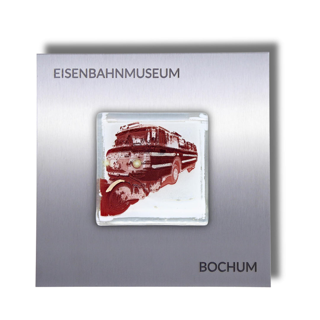 Edition 5/12. Pott Glas Wand-Potträt mit Schi-Stra-Bus-Motiv in Rot. Foto in Schmelzglas auf Edelstahl. Quadratisches Format mit Gravur „Eisenbahnmuseum Bochum“.
