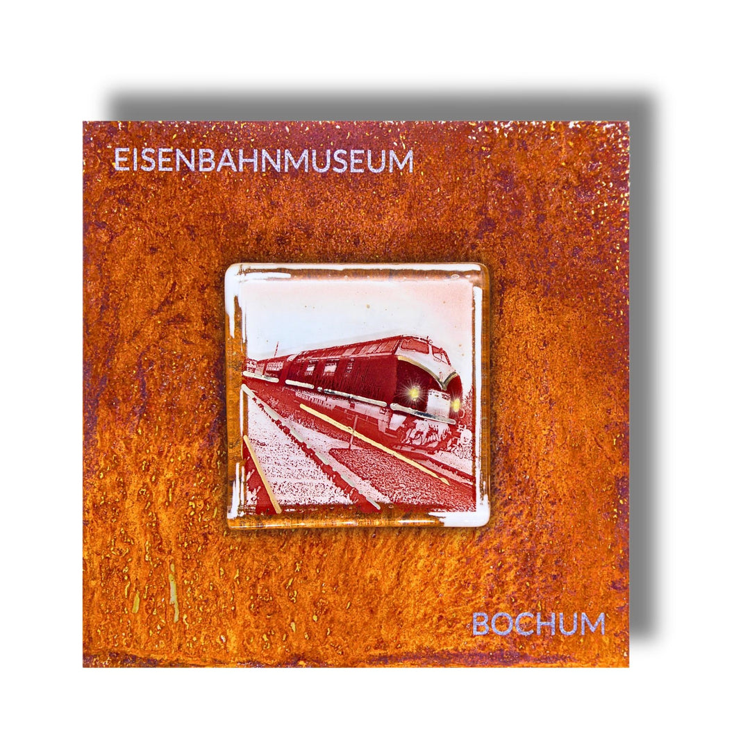 Edition 5/12. Pott Glas Wand-Potträt mit V-Diesellok-Motiv in Rot. Foto in Schmelzglas auf Roststahl. Quadratisches Format mit Gravur „Eisenbahnmuseum Bochum“.