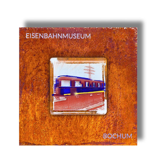Edition 5/12. Pott Glas Wand-Potträt mit Railflex-Motiv in Blau. Foto in Schmelzglas auf Roststahl. Quadratisches Format mit Gravur „Eisenbahnmuseum Bochum“.