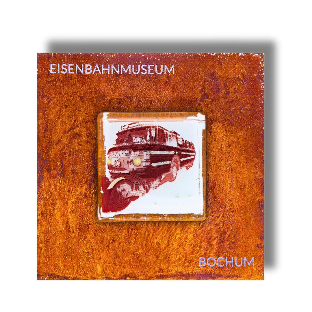 Edition 5/12. Pott Glas Wand-Potträt mit Schi-Stra-Bus-Motiv in Rot. Foto in Schmelzglas auf Roststahl. Quadratisches Format mit Gravur „Eisenbahnmuseum Bochum“.
