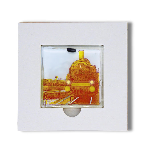 Bochum Edition 05/12. Offenes POTT GLAS Karten-Inlay mit quadratischer Aussparung und Entnahmeaussparung. Darin ein Magnet-POTTRÄT aus Schmelzglas mit gelbem Dampflok-Motiv sowie Akzenten aus 24-Karat-Flüssiggold und Platin.