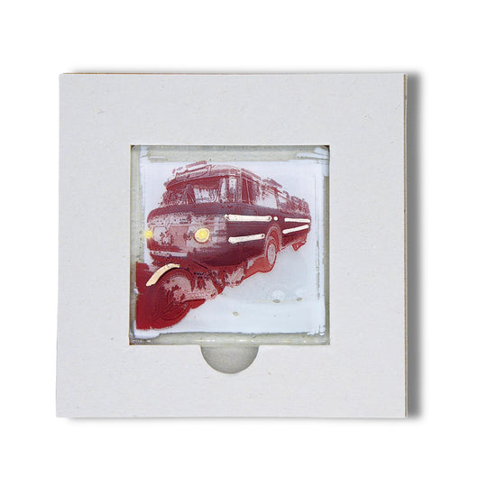 Bochum Edition 05/12. Offenes POTT GLAS Karten-Inlay mit quadratischer Aussparung und Entnahmeaussparung. Darin ein Magnet-POTTRÄT aus Schmelzglas mit Schi-Stra-Bus-Motiv in Rot sowie Akzenten aus 24-Karat-Flüssiggold und Platin.
