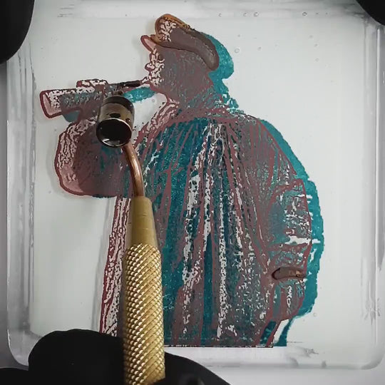 Pott Glas Produktvideo. Zeigt das manuelle Setzen von Akzenten am „Kuhhirte“-Glasbild mit Flüssiggold und Platin.